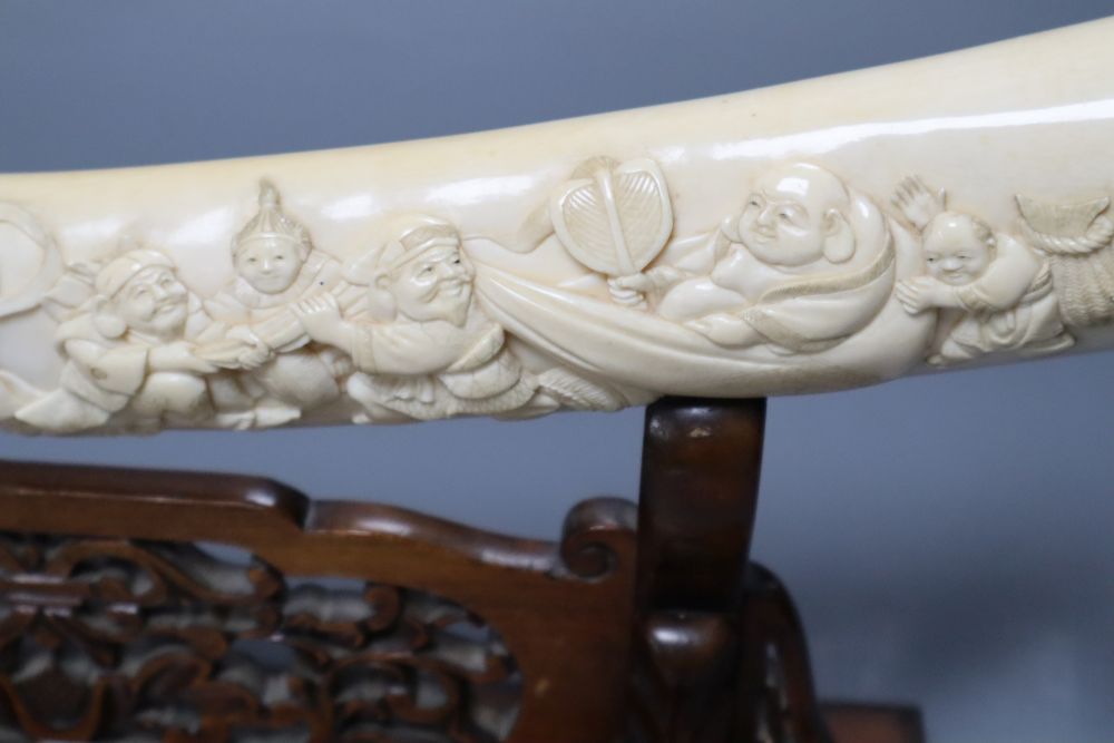 A Japanese ivory Seven immortals tusk carving, early 20th century, wood stand, signed, 44cm excl. stand